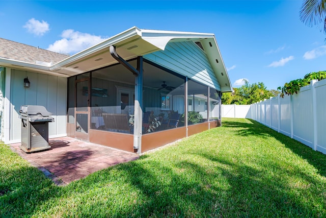 rear view of property featuring a yard, a patio area, a sunroom, and ceiling fan