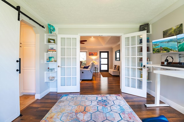 doorway to outside featuring french doors, dark wood-type flooring, a textured ceiling, ornamental molding, and a barn door