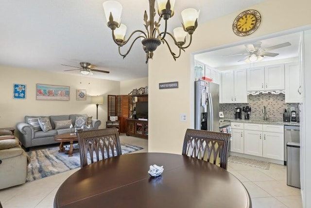 dining space featuring sink, ceiling fan with notable chandelier, and light tile patterned flooring