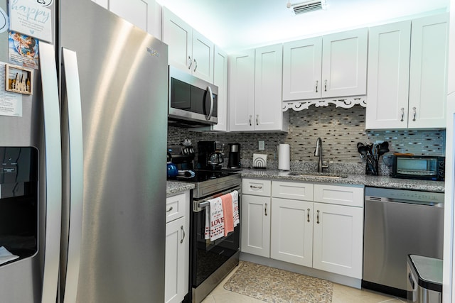 kitchen featuring sink, white cabinetry, tasteful backsplash, stainless steel appliances, and light stone countertops