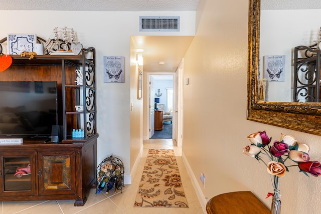 hallway with light tile patterned floors and a textured ceiling