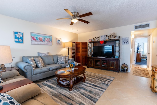 living room featuring light tile patterned floors, a textured ceiling, and ceiling fan