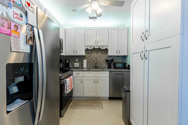 kitchen with white cabinetry, sink, stainless steel appliances, and dark stone counters