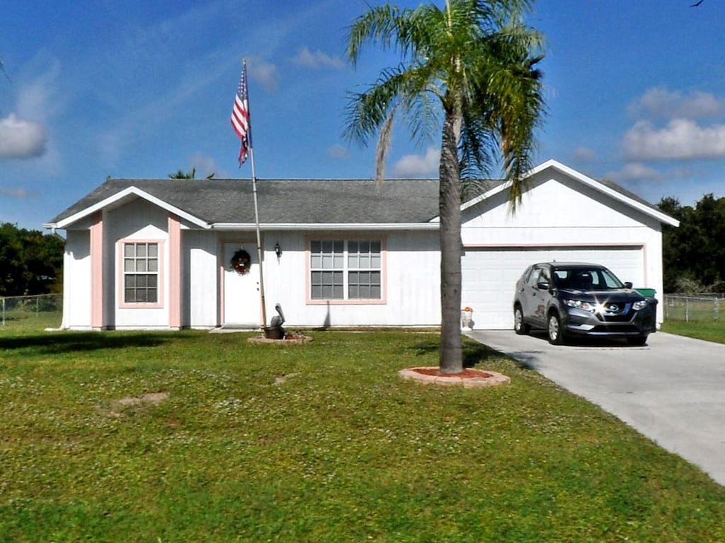 ranch-style house with a garage, driveway, and a front yard