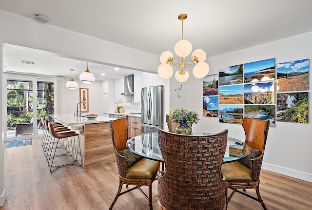 dining room with sink, a notable chandelier, and light hardwood / wood-style floors