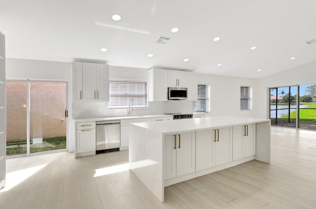 kitchen featuring sink, appliances with stainless steel finishes, white cabinetry, a spacious island, and tasteful backsplash