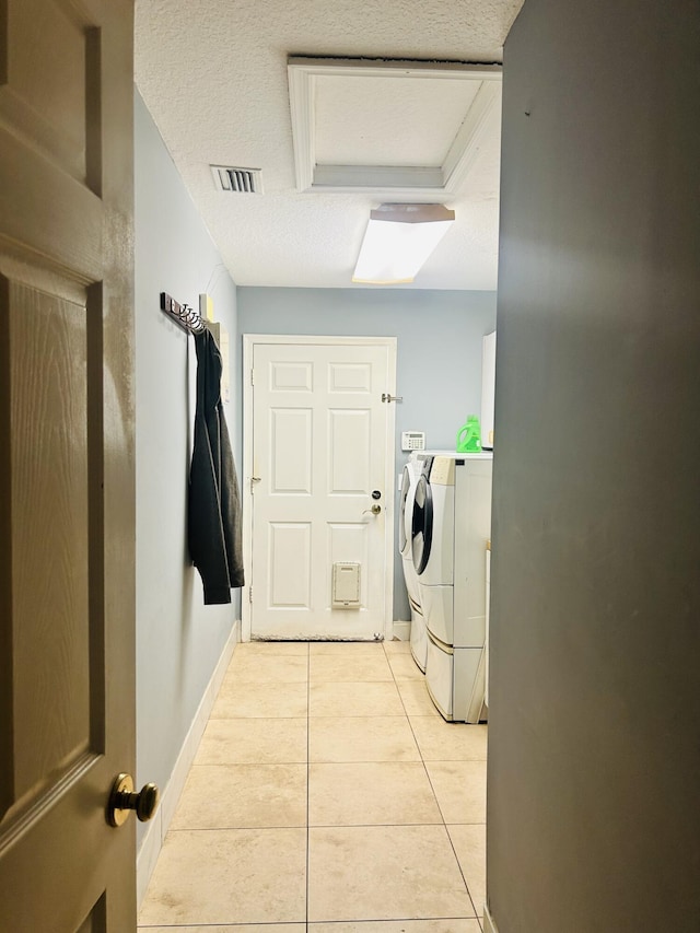 washroom with washer and dryer, light tile patterned floors, and a textured ceiling