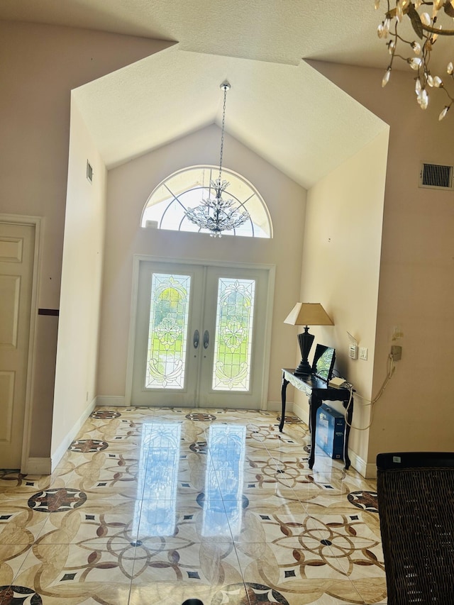 interior space with high vaulted ceiling, french doors, and a chandelier