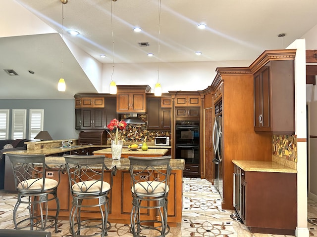 kitchen featuring a kitchen breakfast bar, tasteful backsplash, hanging light fixtures, and double oven