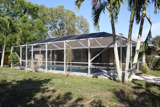 rear view of house with a lanai and a lawn