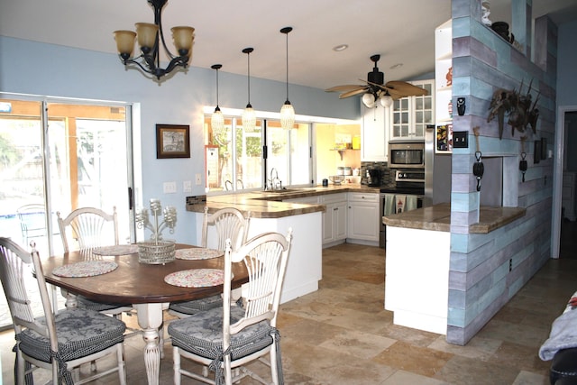 dining space with sink and ceiling fan with notable chandelier