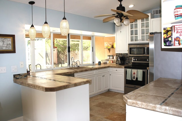 kitchen featuring stainless steel appliances, decorative backsplash, decorative light fixtures, white cabinetry, and kitchen peninsula