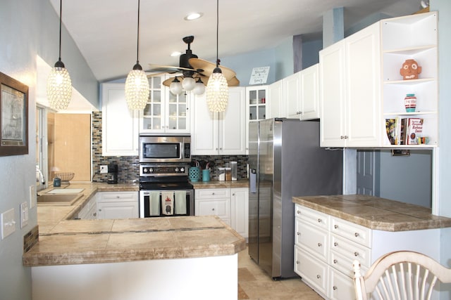 kitchen with kitchen peninsula, hanging light fixtures, sink, appliances with stainless steel finishes, and white cabinets