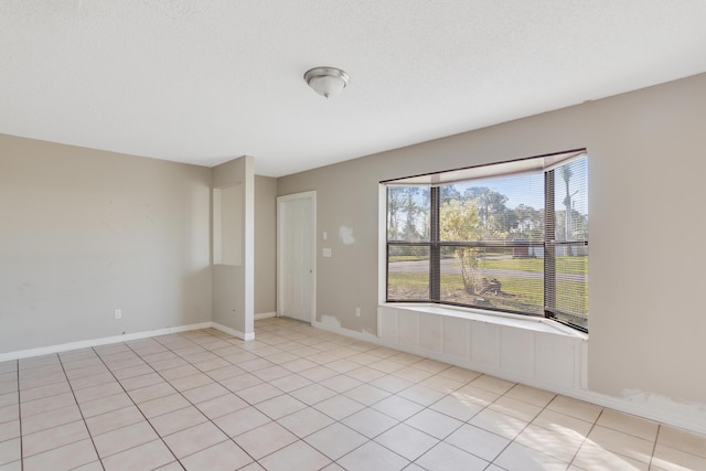 tiled empty room with a textured ceiling