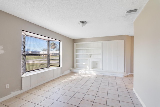 tiled spare room with built in features and a textured ceiling