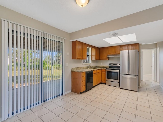 kitchen featuring light tile patterned flooring, a skylight, sink, light stone counters, and stainless steel appliances