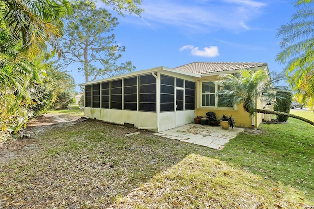 rear view of property with a sunroom, a yard, and a patio area