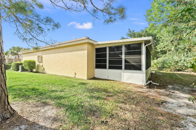 view of side of home with a sunroom, a yard, and cooling unit