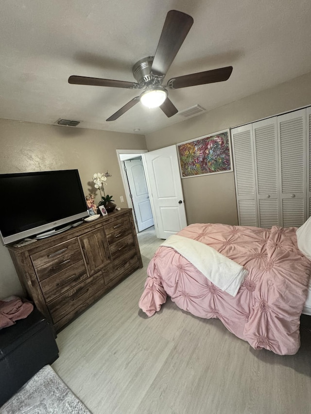 bedroom with ceiling fan, light hardwood / wood-style floors, and a closet