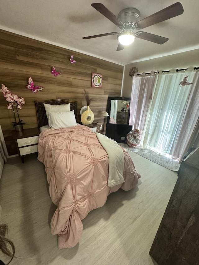 bedroom featuring wood-type flooring, ceiling fan, and wood walls