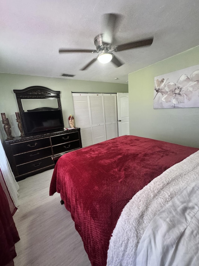 bedroom with ceiling fan, light wood-type flooring, a textured ceiling, and a closet