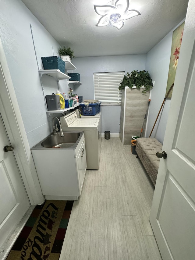 washroom featuring sink, cabinets, independent washer and dryer, a textured ceiling, and light hardwood / wood-style flooring