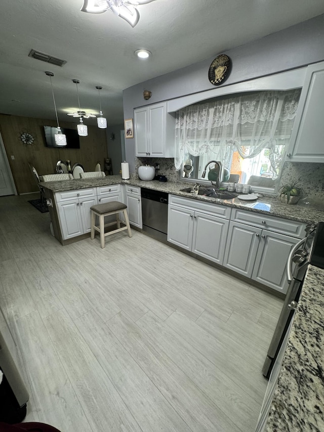 kitchen featuring pendant lighting, sink, dishwasher, tasteful backsplash, and kitchen peninsula