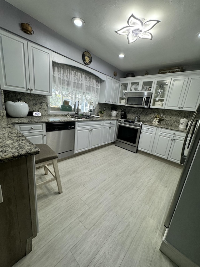 kitchen with stainless steel appliances, dark stone counters, and white cabinets