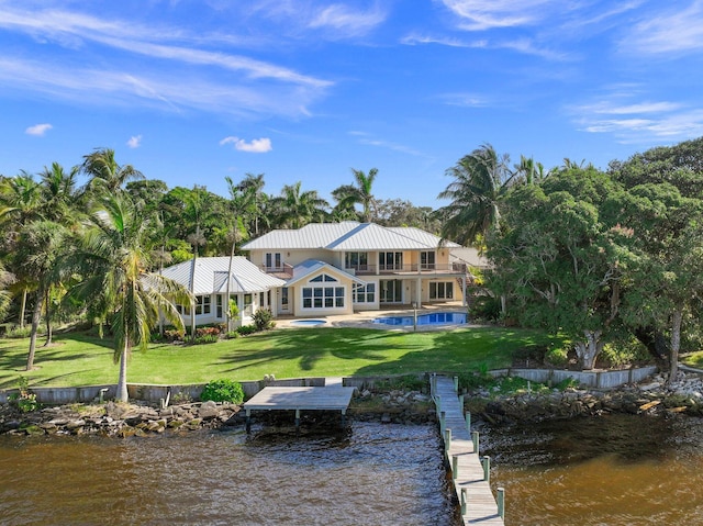 back of house with a water view, a balcony, and a fenced in pool