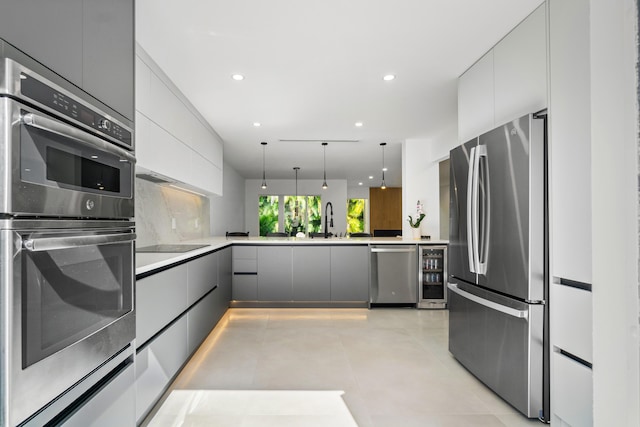 kitchen with pendant lighting, light countertops, gray cabinetry, appliances with stainless steel finishes, and beverage cooler