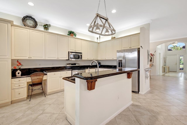 kitchen featuring ornamental molding, stainless steel appliances, an island with sink, and a breakfast bar