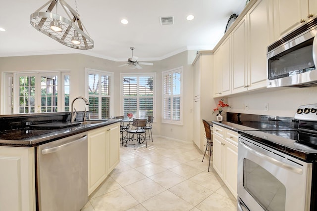 kitchen featuring light tile patterned flooring, crown molding, hanging light fixtures, dark stone countertops, and stainless steel appliances