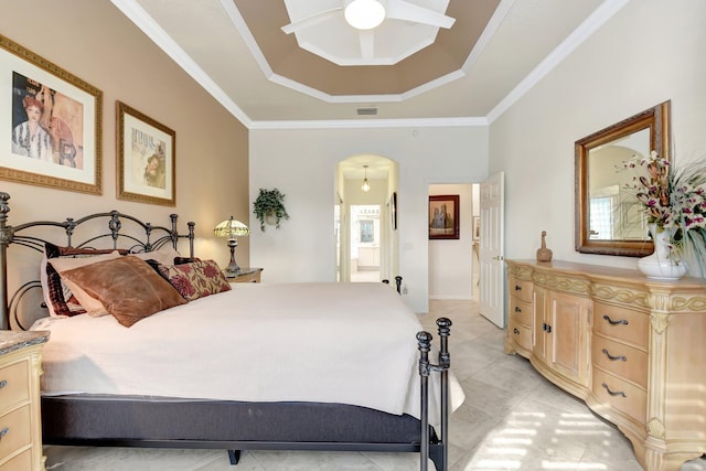 bedroom with ceiling fan, ornamental molding, a tray ceiling, and connected bathroom