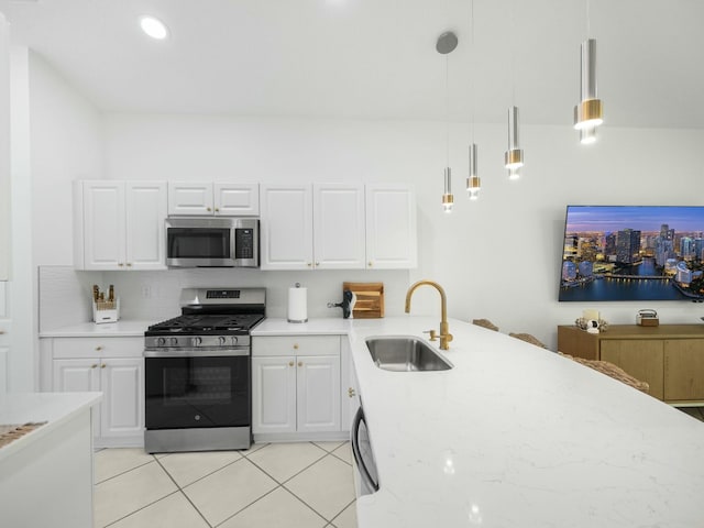 kitchen featuring sink, light stone counters, decorative light fixtures, appliances with stainless steel finishes, and white cabinets