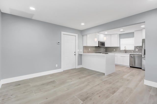 kitchen featuring stainless steel appliances, white cabinetry, tasteful backsplash, and light hardwood / wood-style flooring