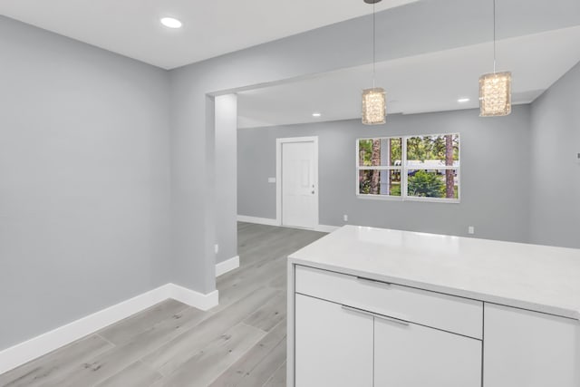 kitchen featuring white cabinetry, light hardwood / wood-style floors, and hanging light fixtures