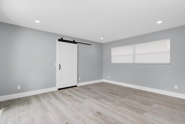 spare room with a barn door and light hardwood / wood-style flooring