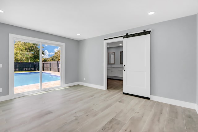 spare room featuring a barn door and light hardwood / wood-style flooring