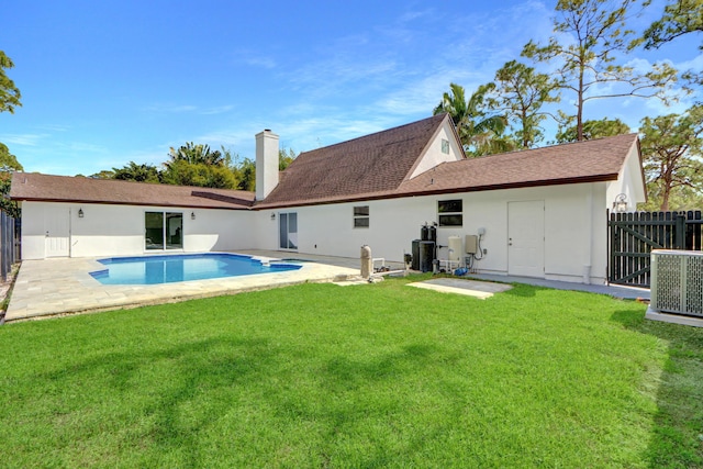 rear view of property with a fenced in pool, a patio, a yard, and central air condition unit