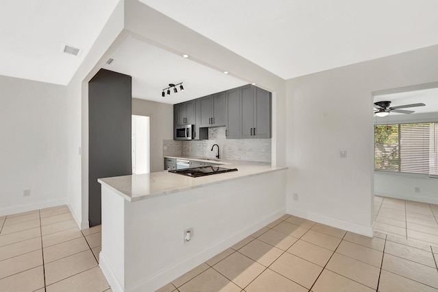 kitchen with sink, backsplash, kitchen peninsula, and light tile patterned floors