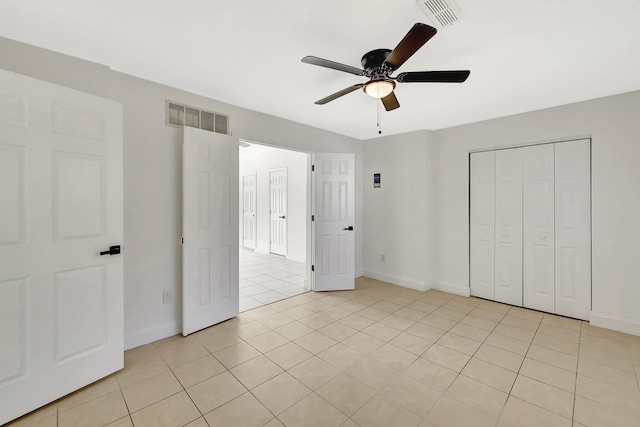 unfurnished bedroom with light tile patterned flooring, ceiling fan, and a closet