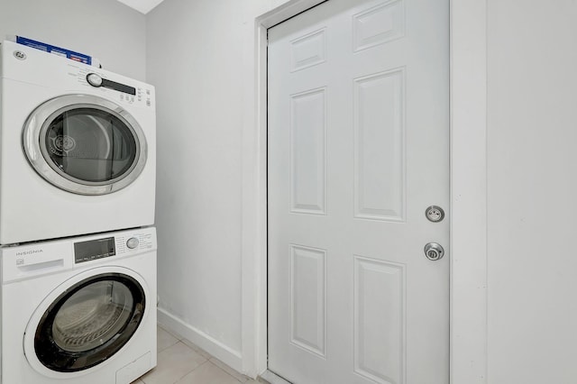 laundry area with stacked washing maching and dryer and light tile patterned floors