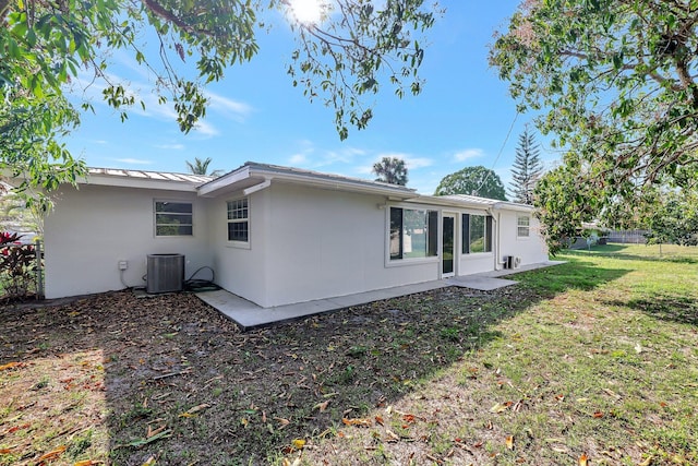 rear view of house with central AC and a lawn