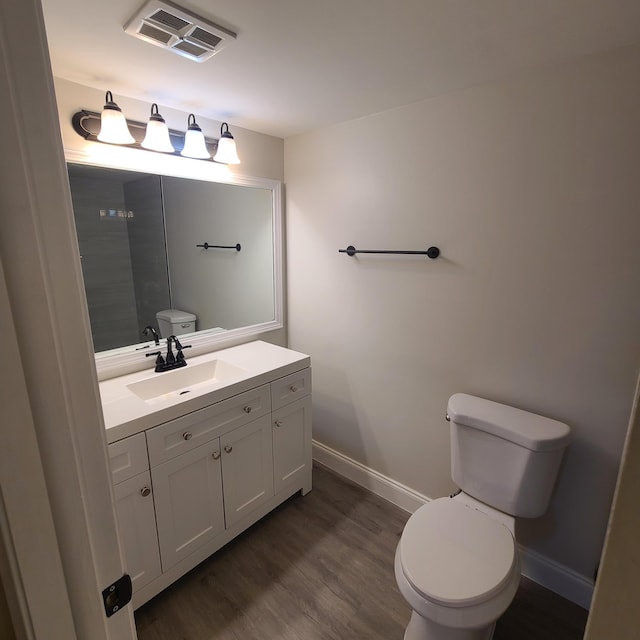 bathroom featuring baseboards, visible vents, toilet, wood finished floors, and vanity