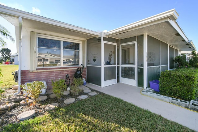 exterior space with a sunroom, brick siding, and a lawn