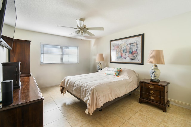 bedroom with a ceiling fan, a textured ceiling, baseboards, and light tile patterned floors