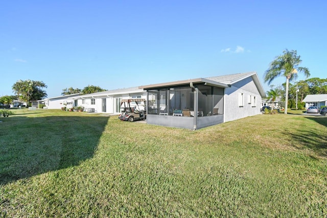 back of house with a sunroom and a lawn