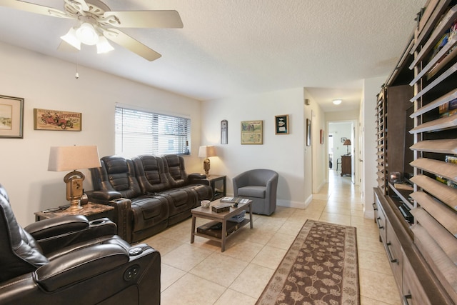 living area featuring ceiling fan, a textured ceiling, baseboards, and light tile patterned floors