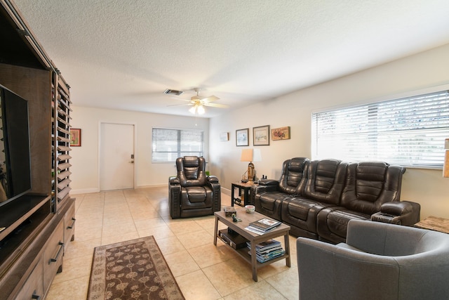 living area with light tile patterned floors, visible vents, ceiling fan, a textured ceiling, and baseboards