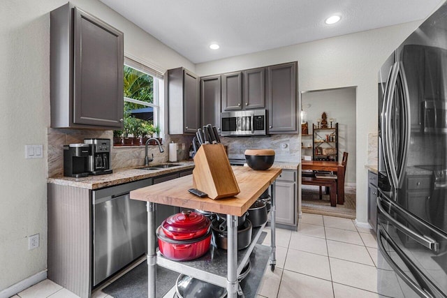 kitchen featuring tasteful backsplash, appliances with stainless steel finishes, sink, and light tile patterned floors